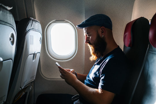 Caucasian man using phone into the airplane