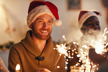 Portrait of cheerful bearded man wearing santa hat while enjoying Christmas celebration with...