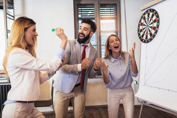 Business people making team training exercise during team building seminar, play darts. Indoor team building activities.