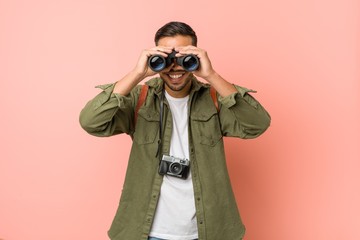 Young south-asian man looking through a binoculars.