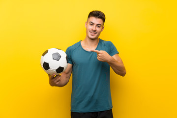 Handsome young football player man over isolated yellow background with surprise facial expression
