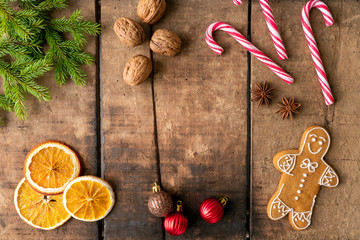 Gingerbread men, candy canes, walnuts, pine branch, anis and dried oranges on wooden rustic background. Christmas and celebration concept. Copy space for text.