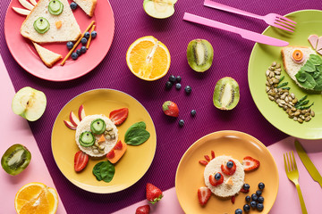 top view of plates with fancy animals made of food near fruits on purple background