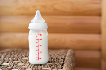 Bottle with breast milk for baby on wooden background. Maternity and baby care concept. Top view....