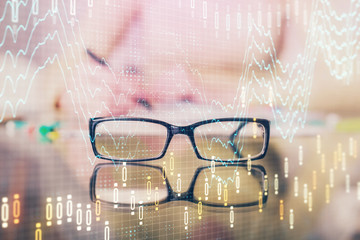 Hand taking notes in notepad. Forex chart holograms in front. Concept of research. Double exposure