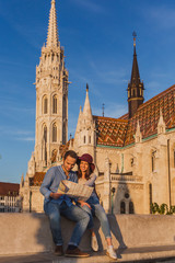 Young couple searching right direction on map from the point from Fisherman Bastion in Budapest with Matthias Church on background