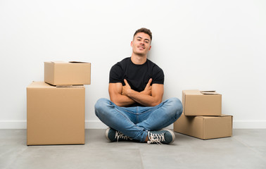 Handsome young man moving in new home among boxes laughing