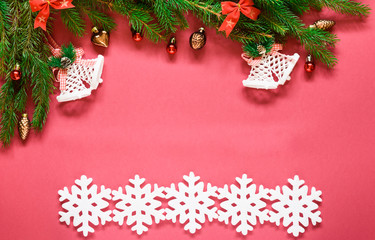 top view, green branches of spruce together with New Year's toys and bows on a pink background