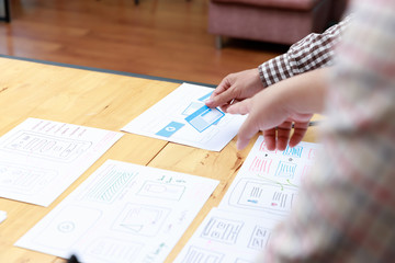 Fototapeta premium Graphic designers work together with UX UI designer planning application template layout framework for mobile phone computer mobile