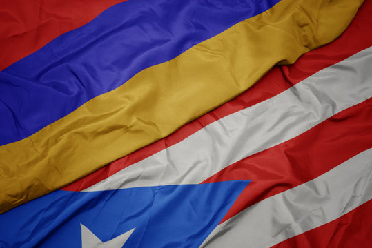 waving colorful flag of puerto rico and national flag of armenia.