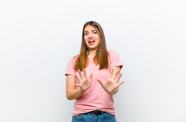 young pretty woman feeling terrified, backing off and screaming in horror and panic, reacting to a...