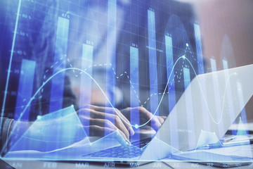 Double exposure of market chart with man working on computer on background. Concept of financial analysis.