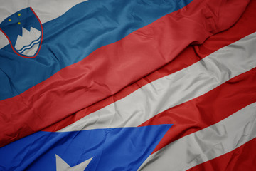 waving colorful flag of puerto rico and national flag of slovenia.