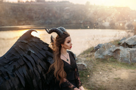 Fabolous character dark fairy, fallen angel demon hell. Woman in carnival gothic latex costume with horns. Black leather wings. Fashion design. perfect skin. Magic sun rays light. flying long hair