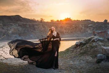 Fantasy sorceress in black fluttering silk dress with horns on her head. Dark gothic fashion...