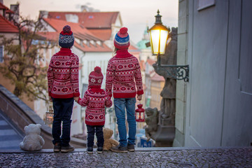Beautiful children, three boy brothers, casually dressed, looking at night view of Prague city