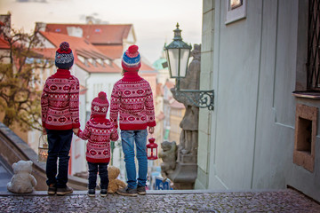 Beautiful children, three boy brothers, casually dressed, looking at night view of Prague city