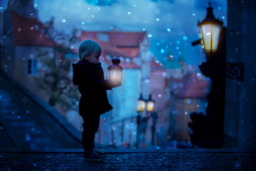 Beautiful toddler child with lantern and teddy bear, casually dressed, looking at night view of...