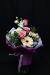 Beautiful bouquet with pink roses and gerberas on a black background.