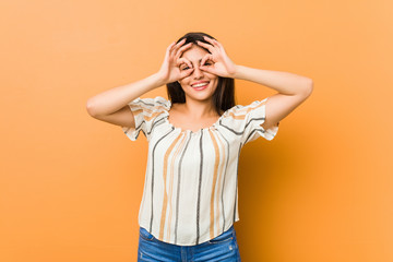 Young curvy woman showing okay sign over eyes