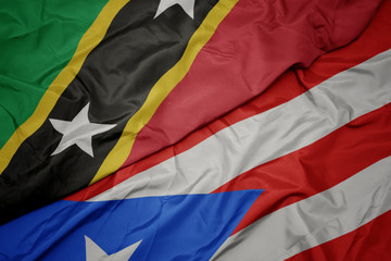 waving colorful flag of puerto rico and national flag of saint kitts and nevis.
