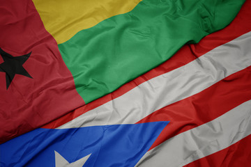 waving colorful flag of puerto rico and national flag of guinea bissau.