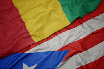 waving colorful flag of puerto rico and national flag of guinea.