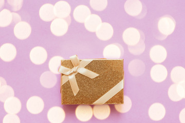 Flat lay of romantic gift decorated with ribbon on pink background