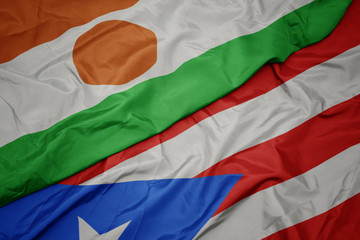 waving colorful flag of puerto rico and national flag of niger.