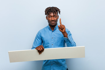Young rasta black man holding a placard showing number one with finger.