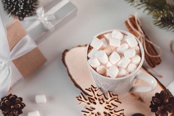 hot chocolate with marshmallows, snowflake, cones, fir branch, gift boxes with white ribbons