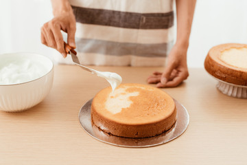 pastry chef puts cream on a sponge cake. Cake making process.
