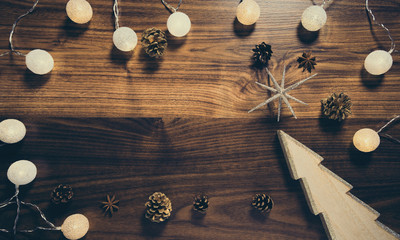 Wooden background with decorative christmas tree, garland and pine cones. Celebration and holiday concept. Top view.