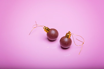 Two christmas New Year balls made of chocolate on a pale pink background. View from above.