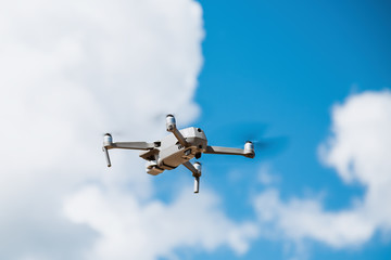 Gray drone flies against the sky with clouds