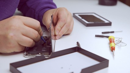 Phone repairman repairing a smartphone via warranty