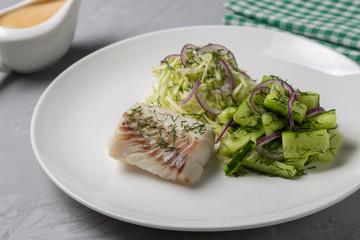 Boiled cod salad with cucumber, cabbage and red onion. Dish for people with diabetes and overweight