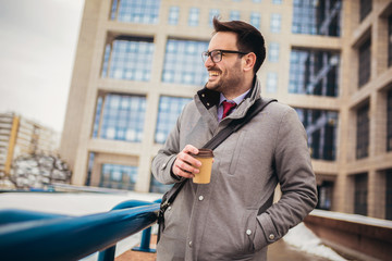 Confident young man in glasses drinking coffee outdoors
