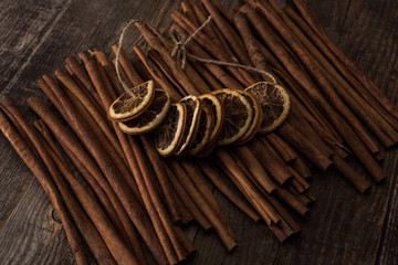 dried orange slices on thread and cinnamon on wooden background