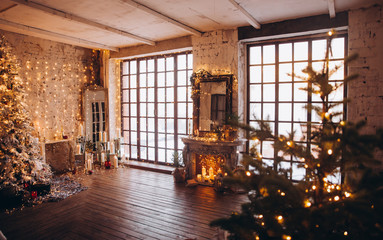 warm cozy evening luxury Christmas room interior design, Xmas tree decorated by gold lights presents gifts, candles,mirror garland lighting fireplace.holiday living room. New year holidays concept