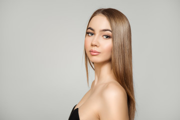 Beautiful woman with straight shiny hair and make-up. Portrait on a gray background. Clean skin,...