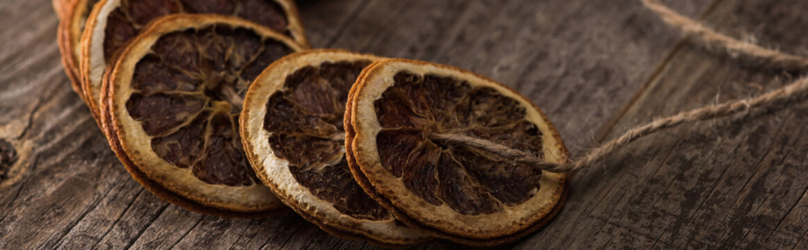 dried orange slices on thread on wooden table, panoramic shot