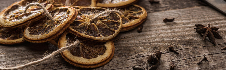 dried citrus slices on rope near anise on wooden surface, panoramic shot