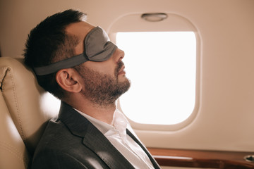 side view of businessman in sleeping mask sitting in private jet