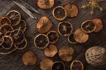 top view of dried citrus and apple slices near snowflake, rope and scissors on wooden surface