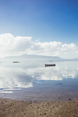 Fototapeta na wymiar Peace and calm – Boats in the still water with clouds in the sky and reflection in the water
