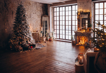 warm cozy evening luxury Christmas room interior design, Xmas tree decorated by gold lights presents gifts, candles,mirror garland lighting fireplace.holiday living room. New year holidays concept