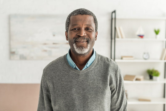 cheerful african american man in grey pullover smiling at camera