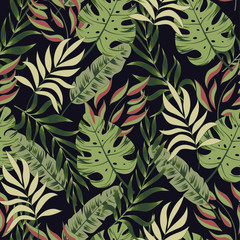 Trend seamless tropical pattern with bright green and yellow plants and leaves on a black background. Beautiful seamless vector floral pattern. Trendy summer Hawaii print.