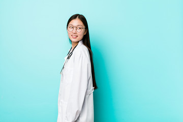 Young chinese doctor woman looks aside smiling, cheerful and pleasant.
